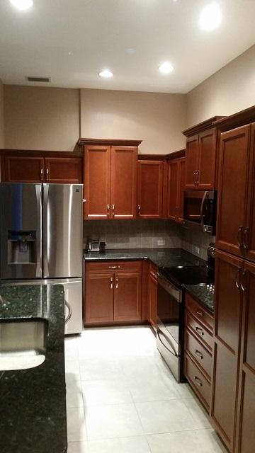After pictures of what once were plain white cabinets but now are beautifully refaced with a rich wood style by Kitchen Facelifts.